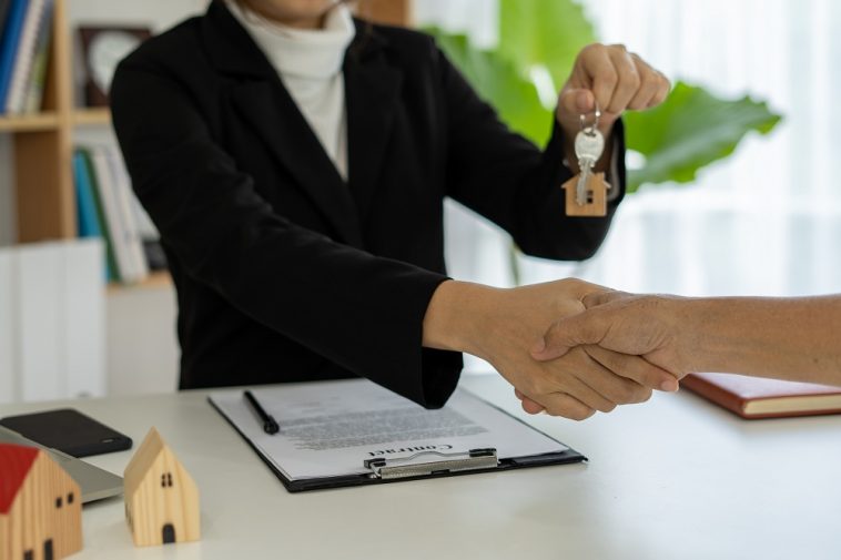 O representante de vendas aperta as mãos e entrega as chaves para os novos proprietários representado o aumento na procura de consórcio imobiliário no Brasil em 2021