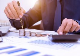 Feche acima, mão que põe a pilha das moedas do dinheiro no dinheiro da economia e no conceito crescente do negócio simulando a portabilidade de crédito