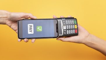 Pessoa que paga com seu aplicativo de carteira para smartphone, simbolizando a tecnologia de pagamento por aproximação do cartão
