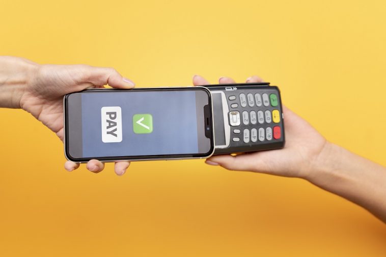 Pessoa que paga com seu aplicativo de carteira para smartphone, simbolizando a tecnologia de pagamento por aproximação do cartão