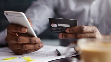 Foto recortada de um empresário afro-americano pagando com cartão de crédito