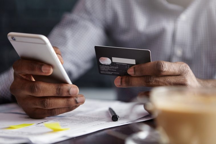 Foto recortada de um empresário afro-americano pagando com cartão de crédito