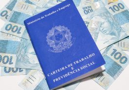 carteira de trabalho CLT em cima de notas de cem reais, simbolizando o saque extraordinário do FGTS liberado pela Caixa