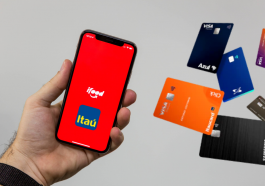 imagem de mão segurando celular na tela do iFood com logo do Itaú e ao lado vários cartões do Itaú em miniatura, pois Agora você pode pedir seu cartão Itaú pelo iFood