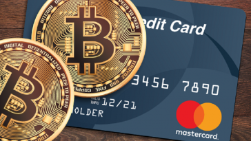 imagem de cartão de crédito da bandeira Mastercard e em cima dele uma moeda de Bitcoin, simbolizando o primeiro cartão de crédito com limite de crédito em criptomoedas