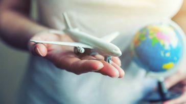 Mãos de mulher feminina segurando um avião modelo de brinquedo pequeno e mapa do globo viajar de avião férias fim de semana aventura