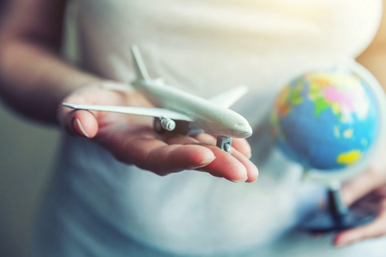 Mãos de mulher feminina segurando um avião modelo de brinquedo pequeno e mapa do globo viajar de avião férias fim de semana aventura