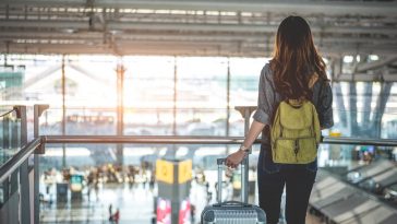 Turista esperando com mala na mão, olhando voo para decolar no aeroporto