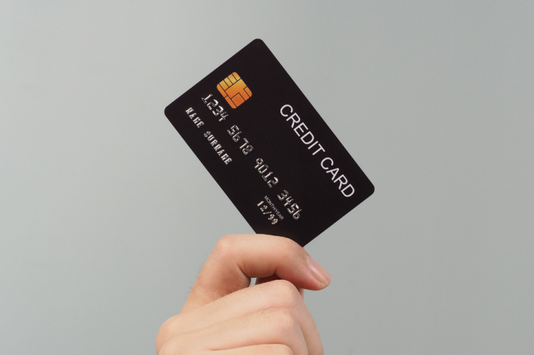 Mão está segurando o cartão de crédito preto simbolizando a renda mínima para ter cartão de crédito aprovado