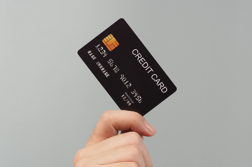 Mão está segurando o cartão de crédito preto simbolizando a renda mínima para ter cartão de crédito aprovado
