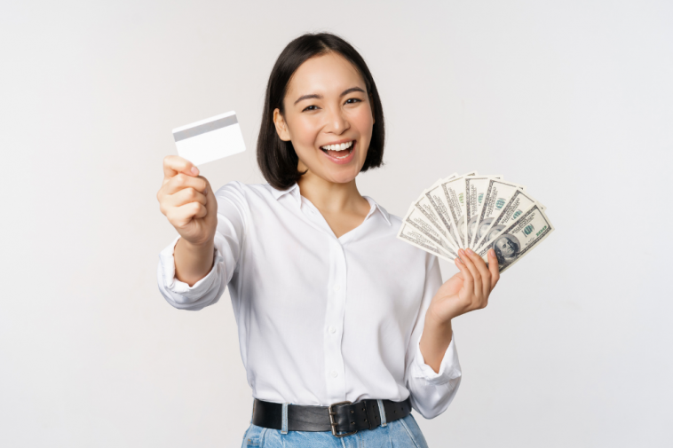 Mulher coreana feliz segurando cartão de crédito e dólares de dinheiro , simbolizando a abertura de conta no exterior com cartão de débito internacional