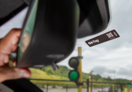 mão masculina mexendo no retrovisor do carro ao lado de um adesivo da C6 Taggy, para simbolizar que a C6 Tag do C6 Bank não será mais grátis para todos os clientes