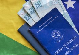 carteira de trabalho do Brasil e notas de cem reais dentro dela e ao fundo uma bandeira do Brasil, para simbolizar o novo valor do salário mínimo para 2023