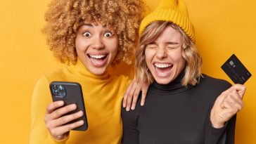 jovens amigáveis riem alegremente usam telefone celular moderno e cartão de crédito simbolizando a abertura de uma conta conjunta