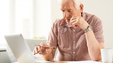 homem idoso mexendo no computador, simbolizando a entrada da aposentadoria