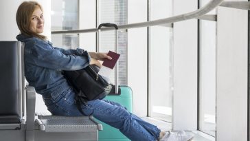 Vista lateral da pessoa segurando o passaporte médico no aeroporto, simulando como ir trabalhar no exterior