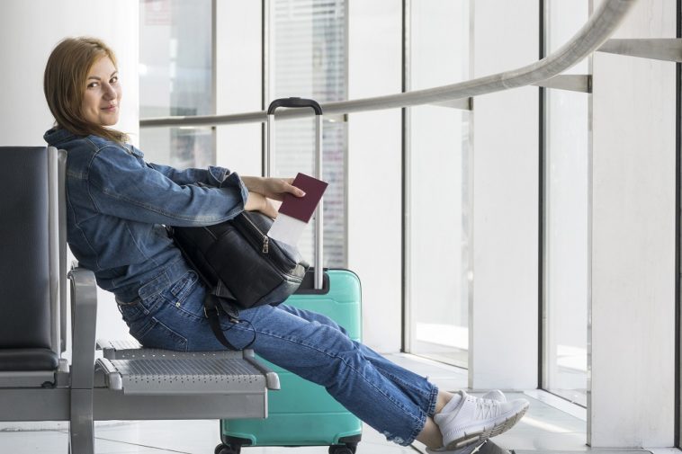 Vista lateral da pessoa segurando o passaporte médico no aeroporto, simulando como ir trabalhar no exterior